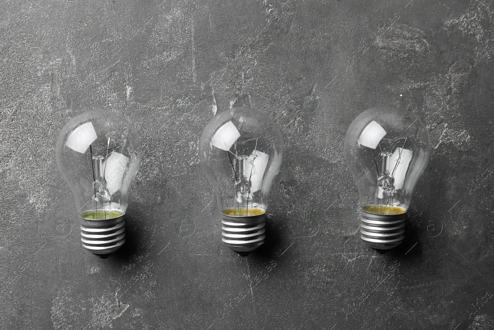 Photo of New incandescent lamp bulbs on grey stone surface, flat lay