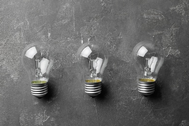 New incandescent lamp bulbs on grey stone surface, flat lay