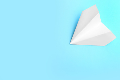 Photo of White paper plane on light blue background, top view. Space for text