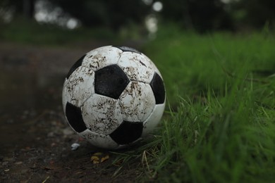 Photo of Dirty leather soccer ball near puddle outdoors