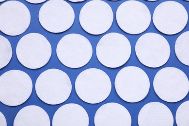 Many cotton pads on blue background, flat lay