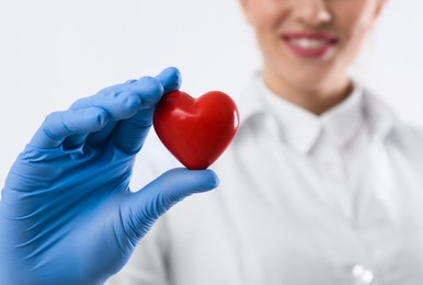 Photo of Doctor holding red heart on white background, closeup with space for text. Cardiology concept
