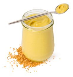 Photo of Glass jar and spoon of tasty mustard sauce with dry seeds isolated on white