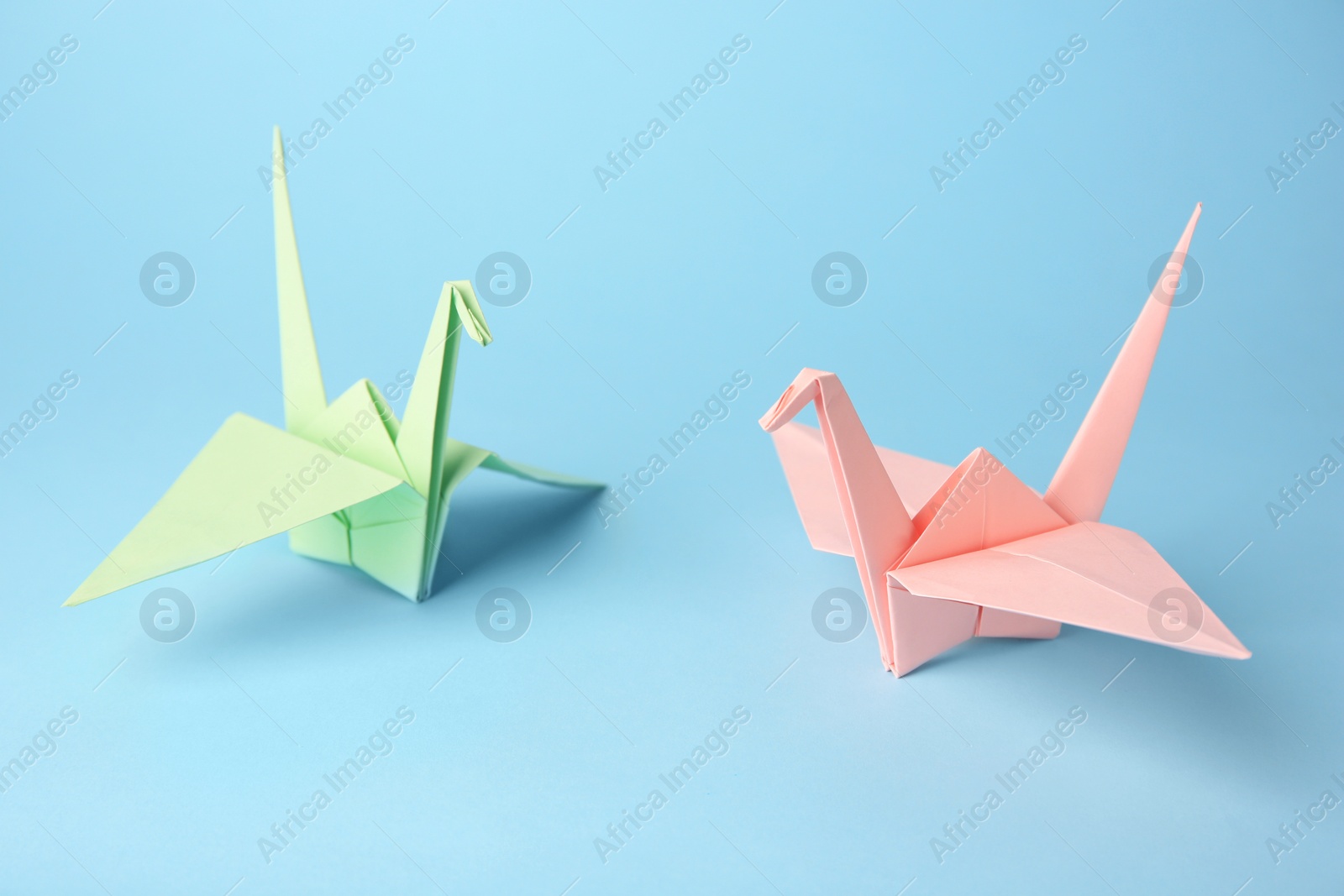 Photo of Origami art. Colorful handmade paper cranes on light blue background