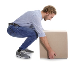 Full length portrait of young man lifting heavy cardboard box on white background. Posture concept