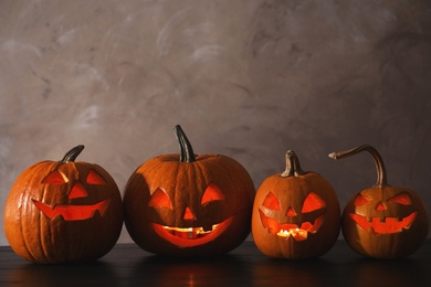Halloween pumpkin head jack lanterns on table against color background