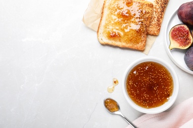 Flat lay composition with delicious fig jam on light grey table. Space for text