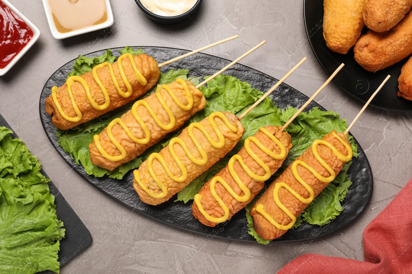 Photo of Delicious corn dogs with mustard served on grey table, flat lay