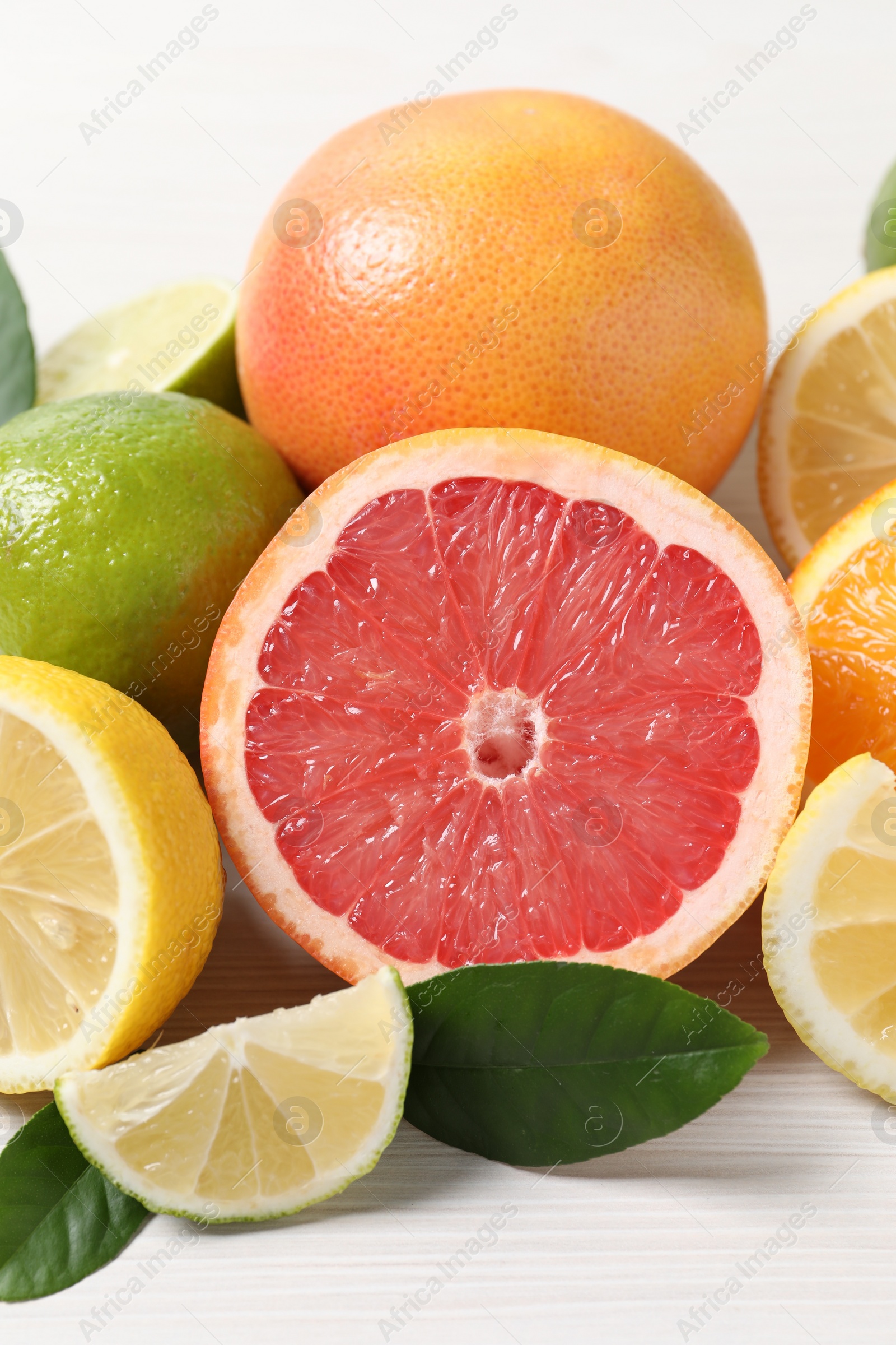 Photo of Different cut and whole citrus fruits on white table, closeup