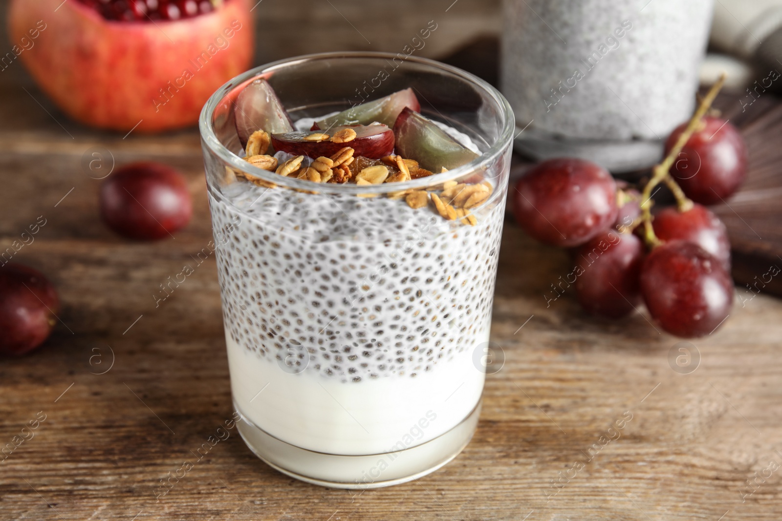 Photo of Tasty chia seed pudding with granola and ingredients on table