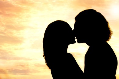 Image of Silhouette of lovely couple kissing at sunset