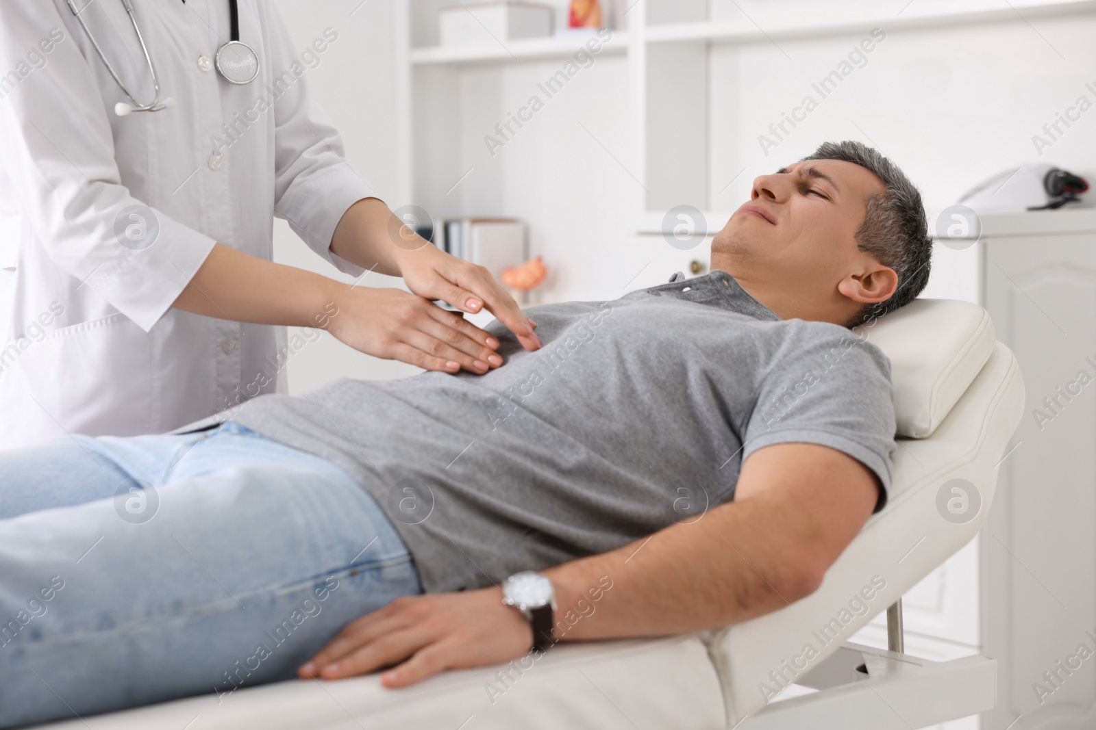 Photo of Gastroenterologist examining patient with stomach pain on couch in clinic, closeup