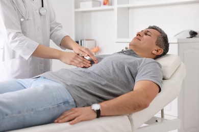 Photo of Gastroenterologist examining patient with stomach pain on couch in clinic, closeup