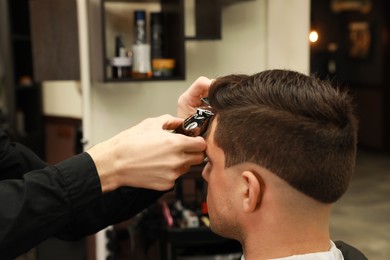 Photo of Professional hairdresser making stylish haircut in salon, closeup