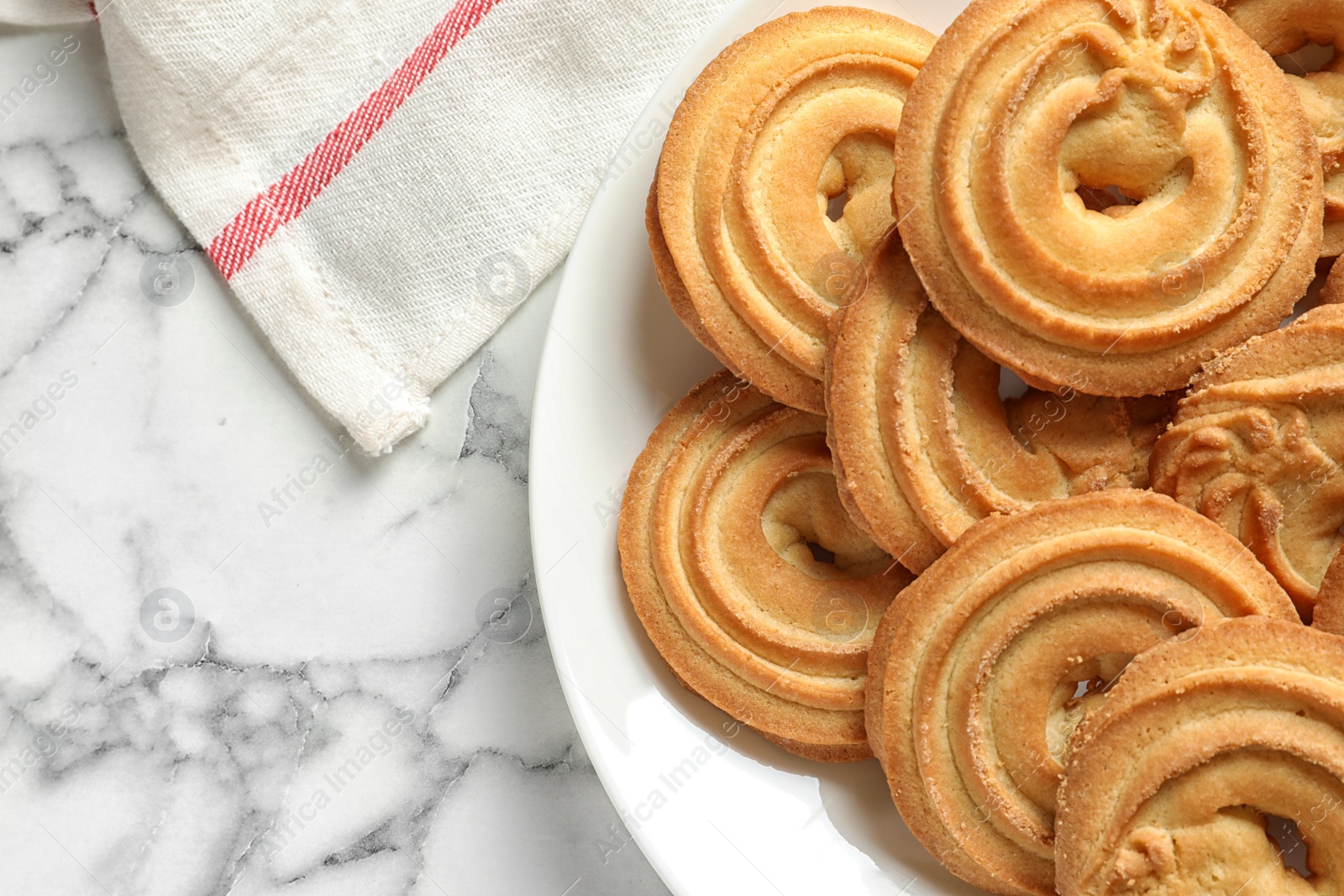 Photo of Plate with Danish butter cookies on marble table, top view. Space for text