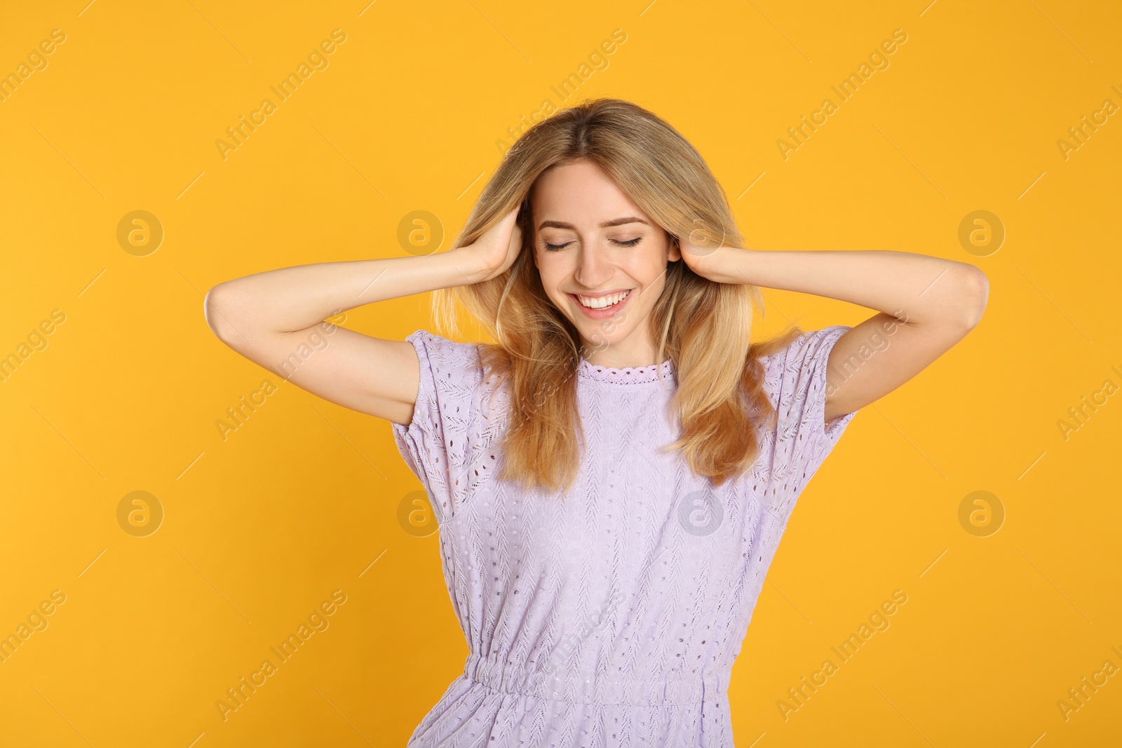 Photo of Portrait of beautiful young woman with blonde hair on yellow background