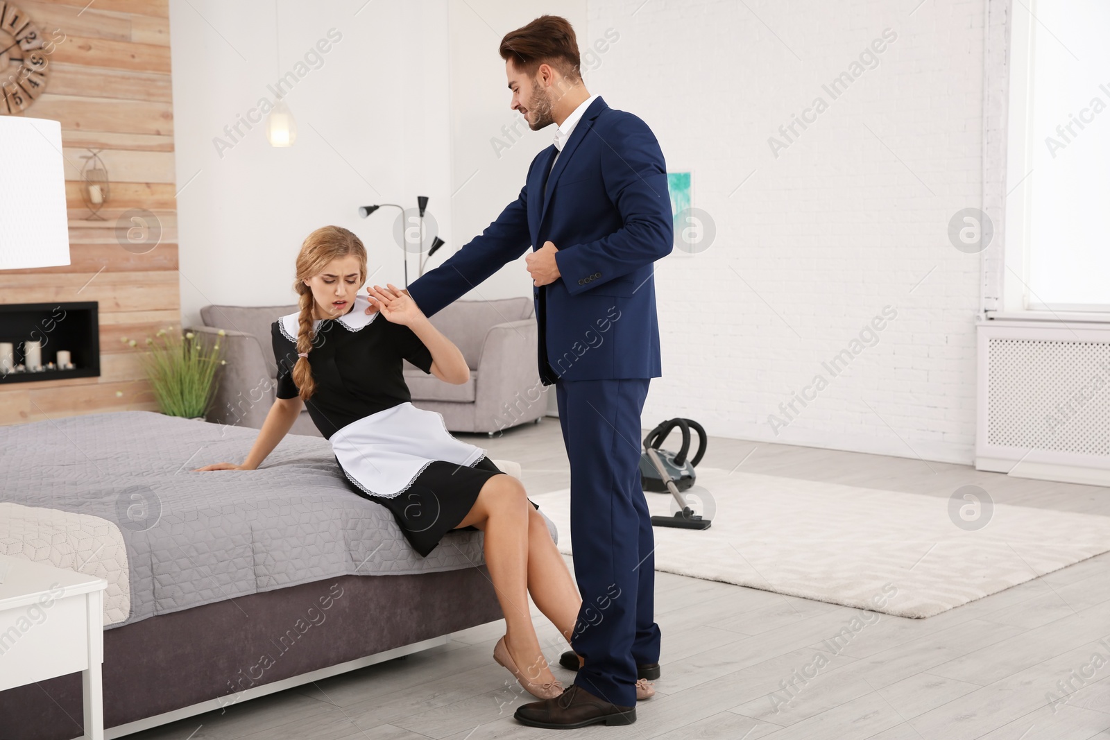 Photo of Young man sexually harassing chambermaid in hotel room. Space for text