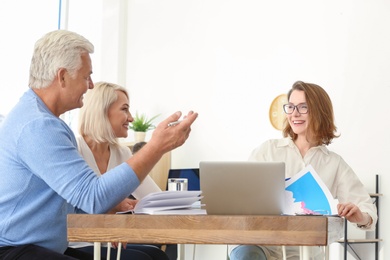 Photo of Female manager consulting mature couple in office