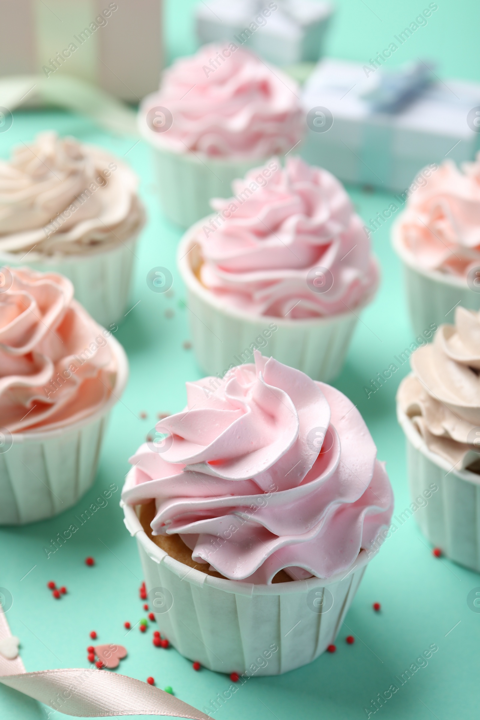 Photo of Delicious birthday cupcakes and sprinkles on turquoise background, closeup