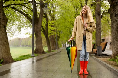 Photo of Young woman with umbrella walking in park on spring day