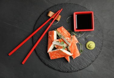 Photo of Fresh crab sticks with soy sauce served on black table, top view
