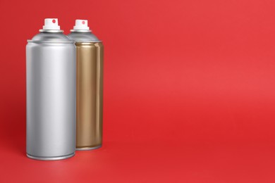 Photo of Cans of spray paints on red background. Space for text