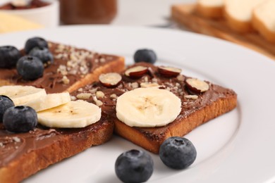 Photo of Toasts with tasty nut butter, banana slices, blueberries and hazelnuts on plate, closeup