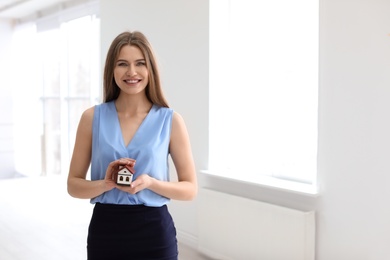 Beautiful real estate agent with house model indoors