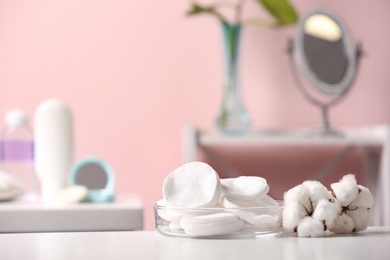 Photo of Cotton flowers and pads on table in bathroom, space for text