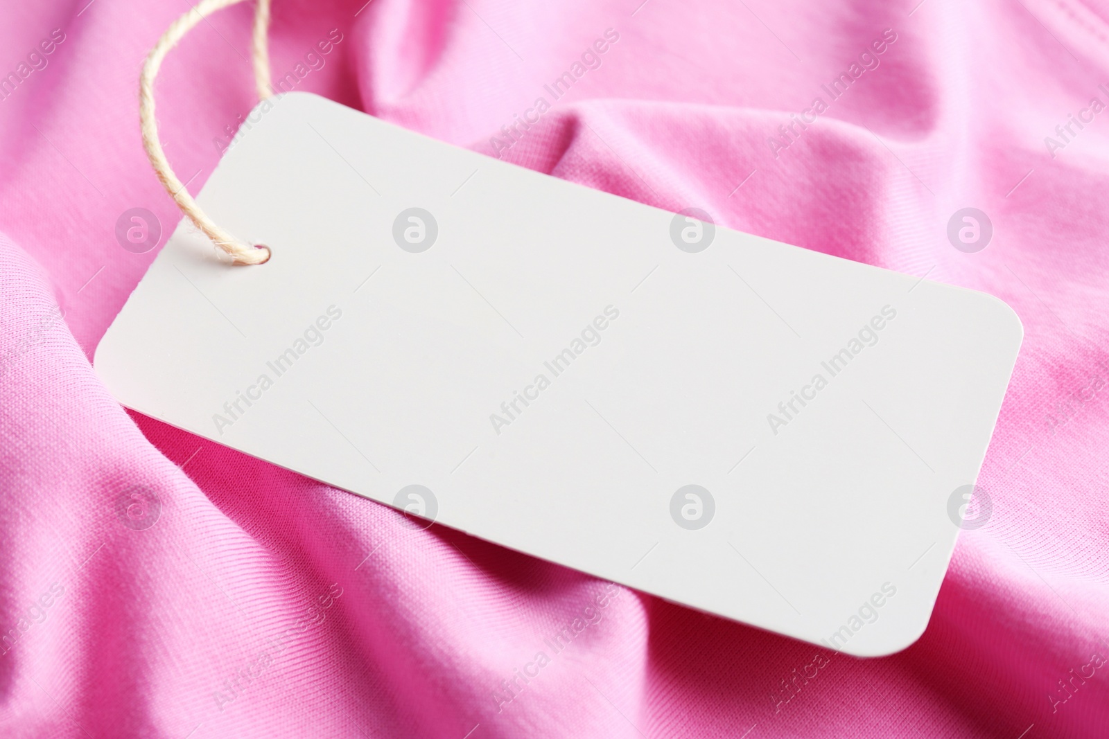 Photo of Cardboard tag with space for text on pink fabric, closeup
