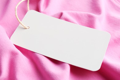 Cardboard tag with space for text on pink fabric, closeup