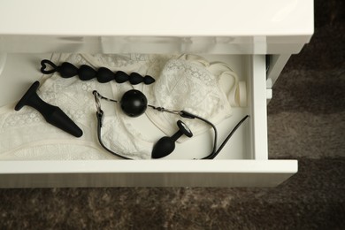 White lingerie and different sex toys in drawer indoors, above view