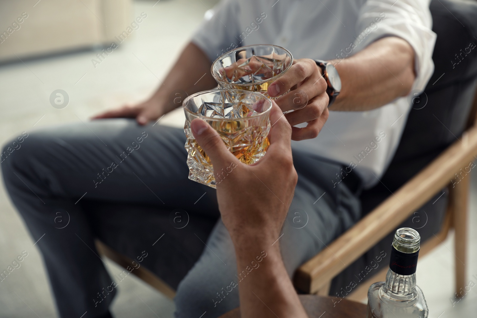 Photo of Young men drinking whiskey together at home, closeup