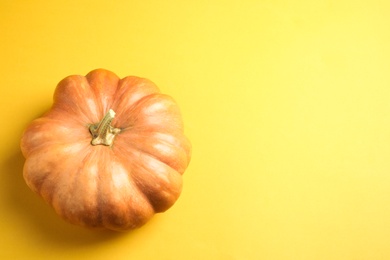 Photo of Fresh ripe pumpkin on yellow background, top view with space for text. Holiday decoration