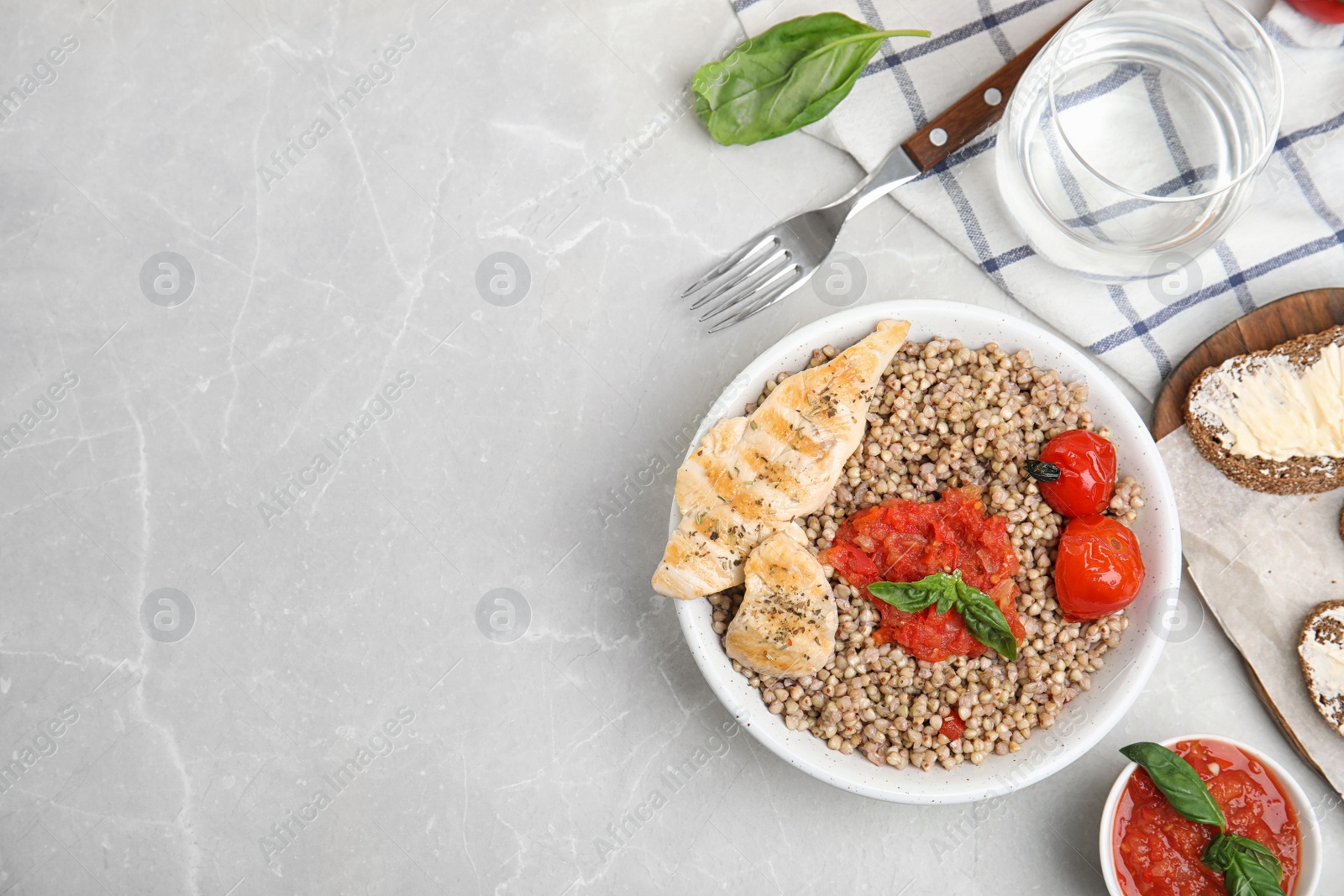 Photo of Tasty buckwheat porridge with meat and vegetables on grey marble table, flat lay. Space for text