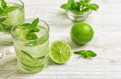 Photo of Refreshing beverage with mint and lime on table