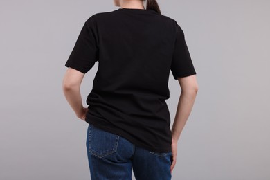 Photo of Woman in stylish black t-shirt light grey on background, back view