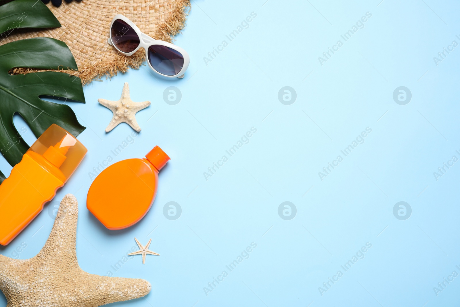 Photo of Flat lay composition with sun protection products and beach accessories on light blue background. Space for text