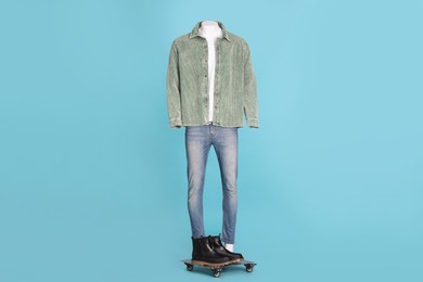Photo of Male mannequin with boots dressed in white t-shirt, jeans and stylish jacket on light blue background