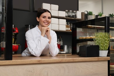 Photo of Portrait of happy baker at desk in her cafe
