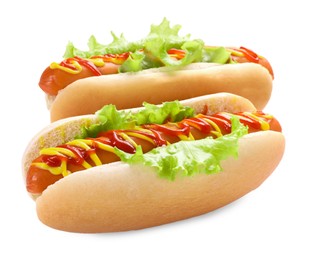 Photo of Tasty hot dogs with lettuce, ketchup and mustard isolated on white