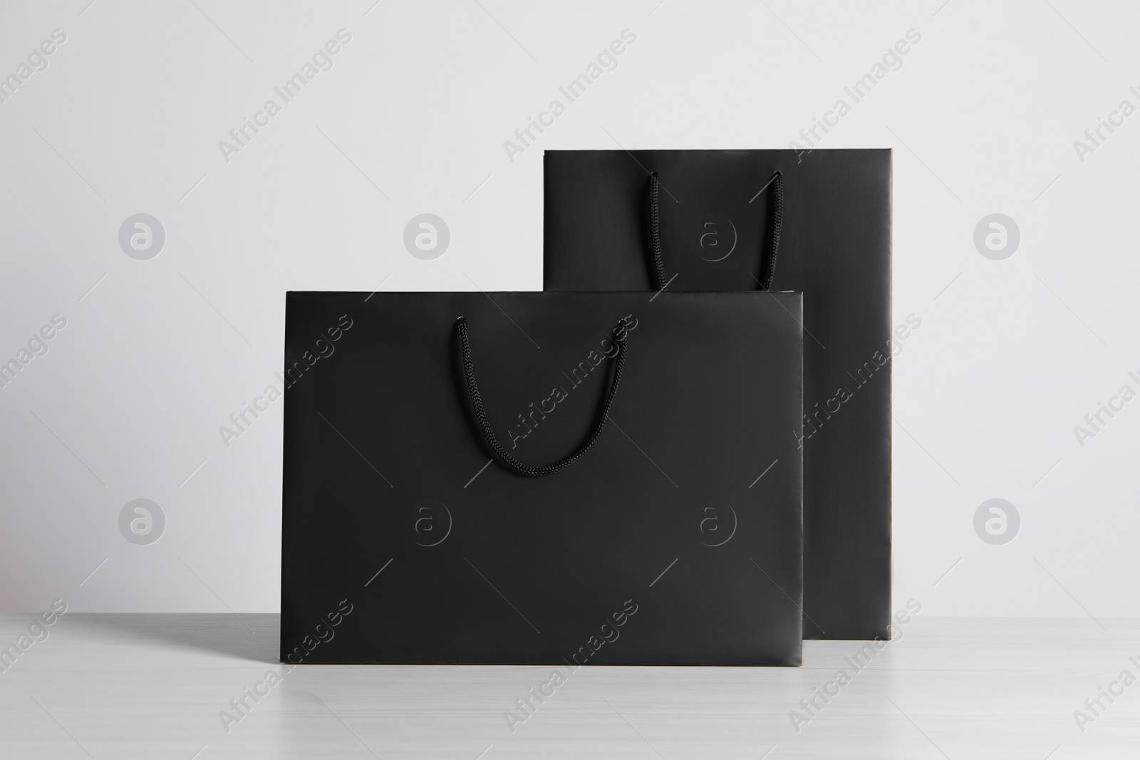 Photo of Black paper bags on white wooden table