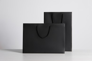 Black paper bags on white wooden table