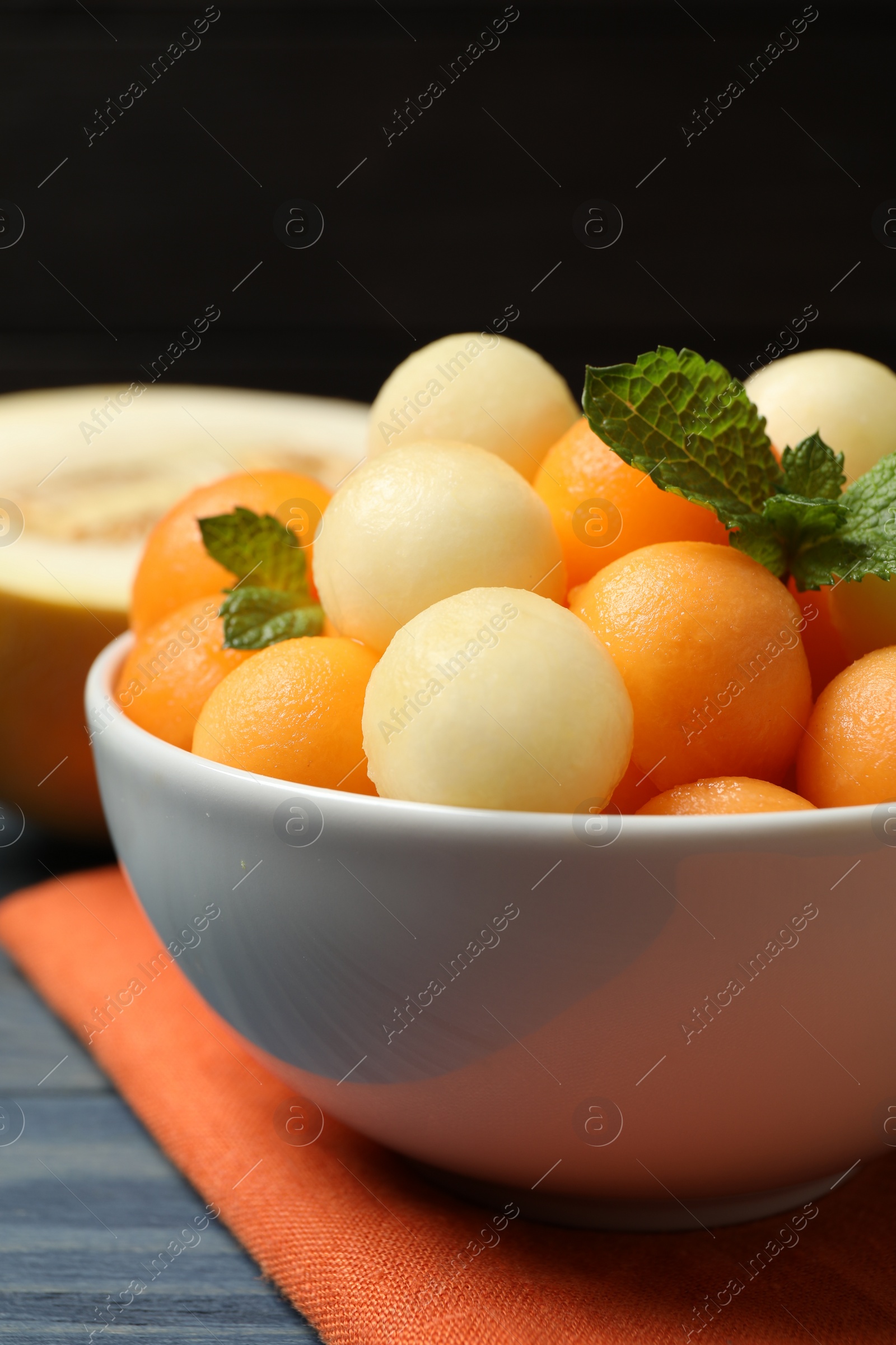 Photo of Melon balls and mint in bowl on table, closeup