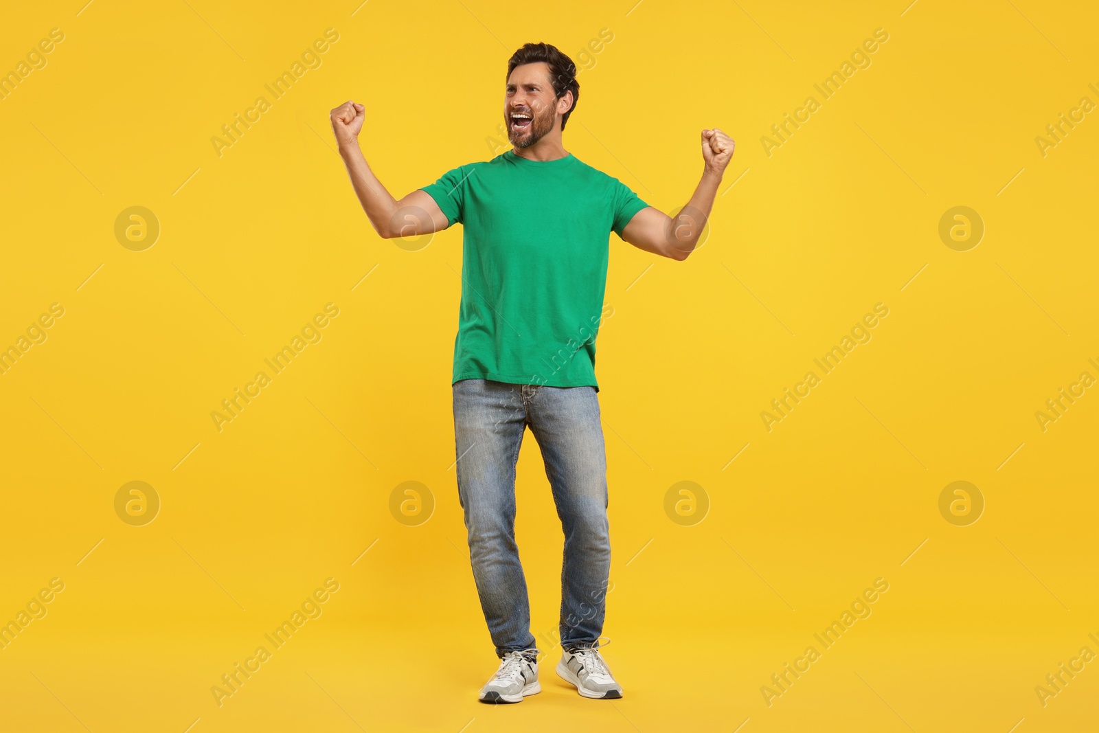 Photo of Emotional sports fan celebrating on yellow background