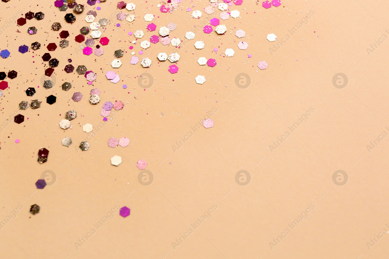 Photo of Shiny bright glitter on beige background. Space for text