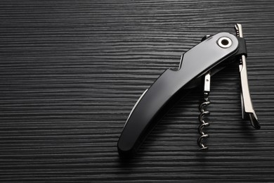 Photo of One corkscrew (sommelier knife) on black wooden table, top view. Space for text