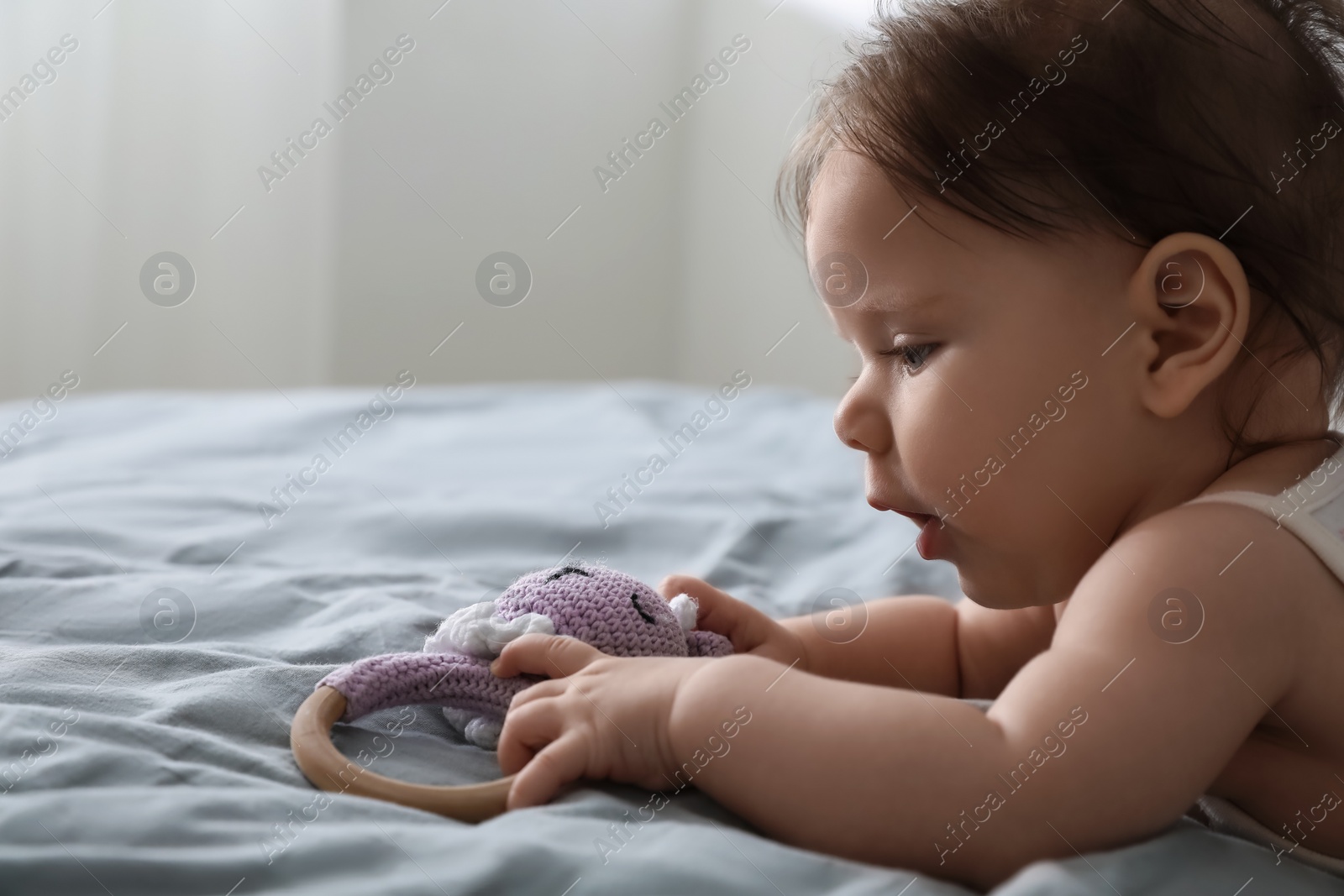 Photo of Cute little baby with toy on bed indoors. Space for text