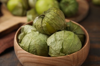 Fresh green tomatillos with husk in bowl on table, closeup