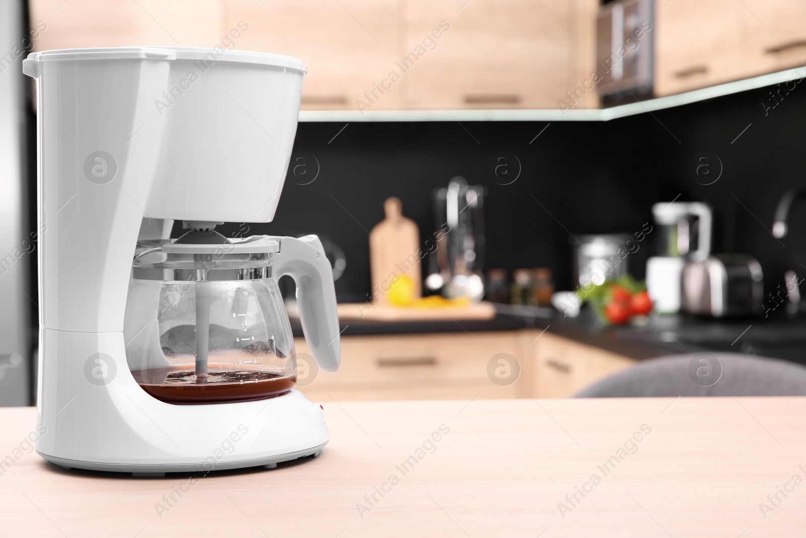 Photo of Modern coffee maker on wooden table in kitchen. Space for text